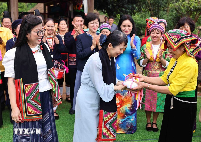 La artesana Lo Thi Tom, representante del grupo étnico Thai, entrega a las dos visitantes la bufanda Pieu y la pelota &apos;con&apos;.