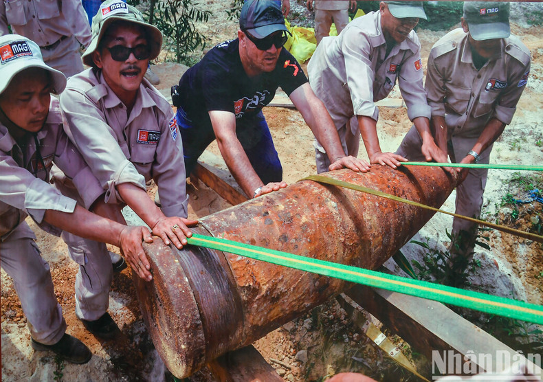 Técnicos del Grupo Asesor de Minas (MAG, en inglés) ayudan a trasladar a un área de desactivación uno de los dos proyectiles de artillería que pesan casi 900 kilogramos descubiertos en la aldea de Thuy Khe, distrito de Gio Linh (foto tomada en abril de 2016).