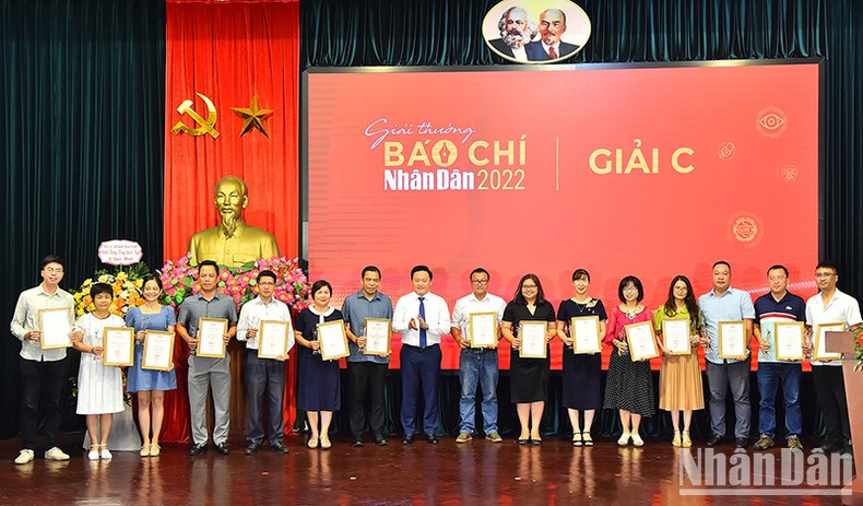 Phan Van Hung, subredactor jefe de Nhan Dan, entrega el premio C a los autores y representantes del grupo de autores.