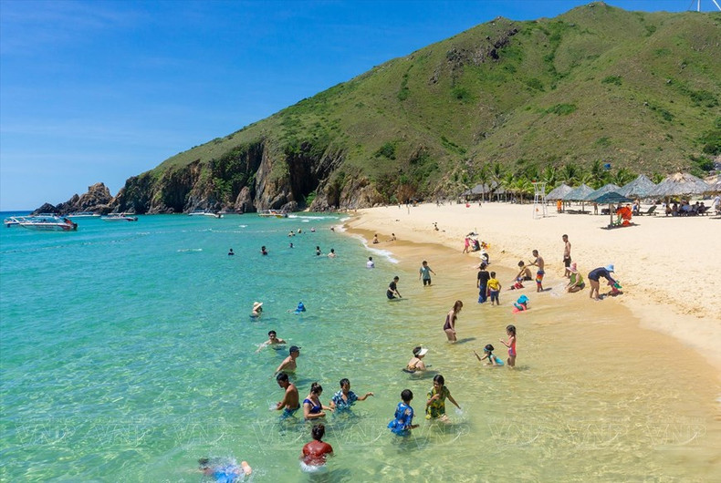 Los turistas se relajan en el fresco mar azul de la playa de Ky Co.