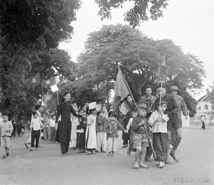 Los niños hanoienes y sus familiares portan banderas para dar la bienvenida a los soldados que liberaron la capital.