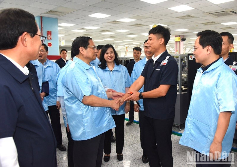 El primer ministro Pham Minh Chinh anima a empleados de la fábrica.