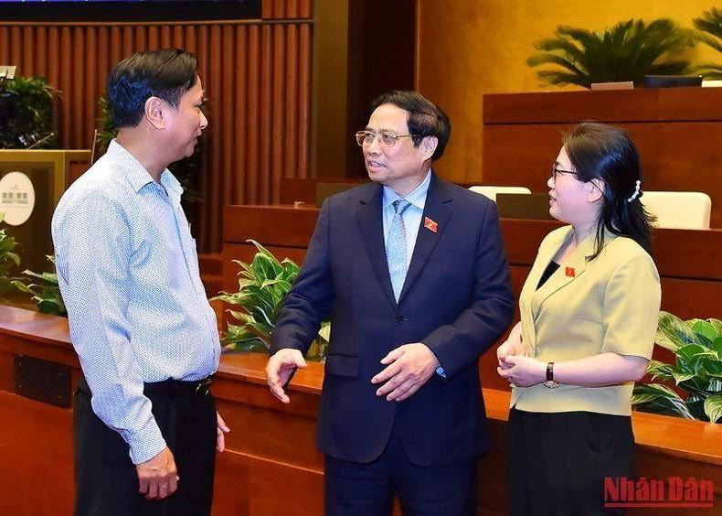 El primer ministro Pham Minh Chinh expresa sus opiniones con los delegados al margen de la reunión.