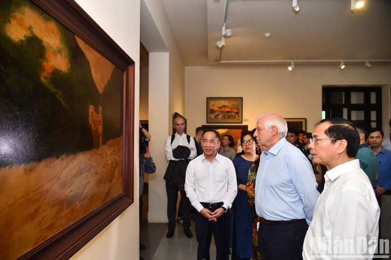 Admiran y escuchan una introducción a la pintura &quot;El tío Ho en la base revolucionaria de Viet Bac&quot; del artista Duong Bich Lien.