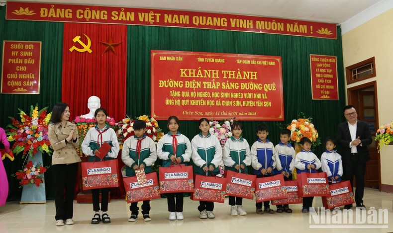 Ejecutivos de Nhan Dan y representantes del Grupo Flamingo otorgan obsequios a estudiantes pobres.