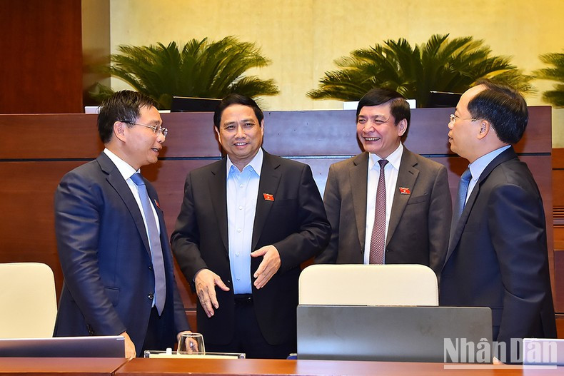 El primer ministro Pham Minh Chinh y el secretario general y presidente de la Oficina de del Parlamento, Bui Van Cuong conversan con el ministro de Transporte, Nguyen Van Thang, al margen de la sesión.