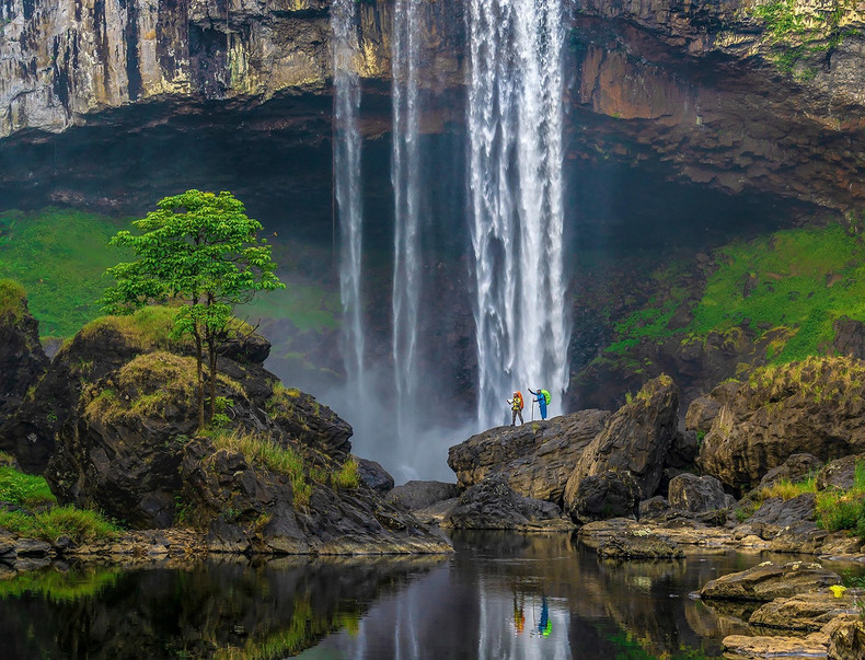 Al pie de la cascada, bloques de piedra con formas interesantes, apilados uno encima del otro, forman grandes escaleras en medio del agua azul plateado.