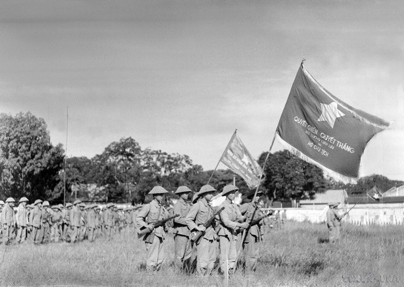 Una unidad de la División de la Capital, enarbolando la bandera “Determinación para luchar, determinación para vencer” entregada por el Presidente Ho Chi Minh realiza la primera ceremonia de izado de bandera después de la liberación de Hanói, en el patio de Cot Co (Torre de la Bandera), actual puerta de Doan Mon de la Ciudadela Imperial de Thang Long.