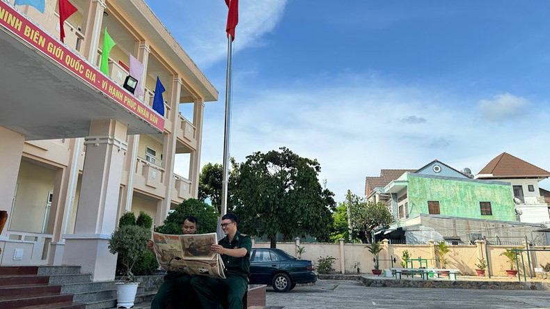 El teniente mayor Nguyen Van Duc, jefe del equipo de movilización de masas, lee el suplemento bajo la bandera nacional.