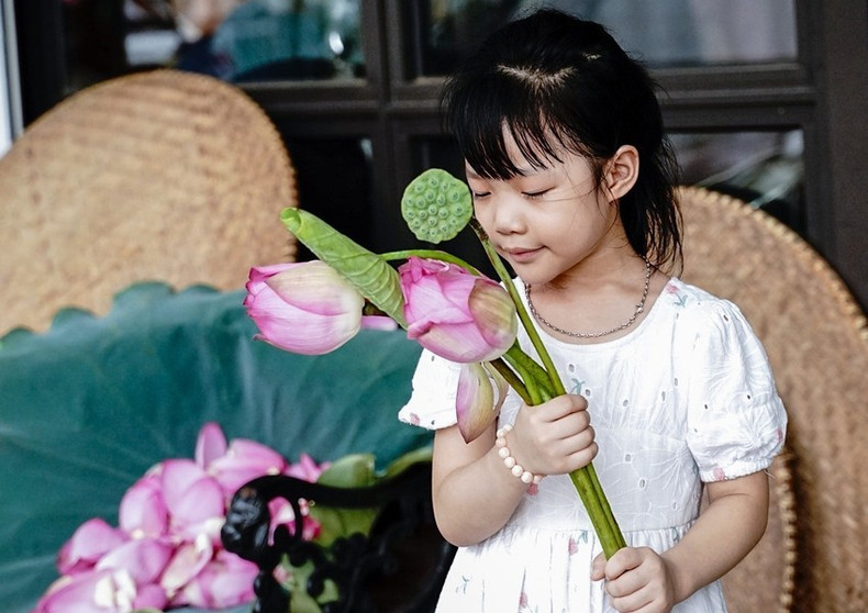 Una niña en el barrio de Quang An junto a las flores de loto de Bach Diep recién cosechadas para marinar el té.