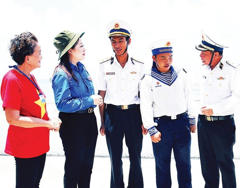 Oficiales del Ejército Popular de Vietnam junto con delegados y compatriotas charlan con soldados en la isla de Len Dao, en Truong Sa, durante una visita en abril de 2023.