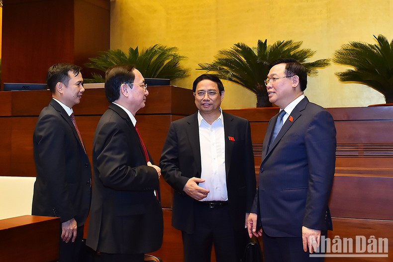 El primer ministro Pham Minh Chinh y el presidente de la Asamblea Nacional Vuong Dinh Hue intercambian opiniones al margen de la sesión.