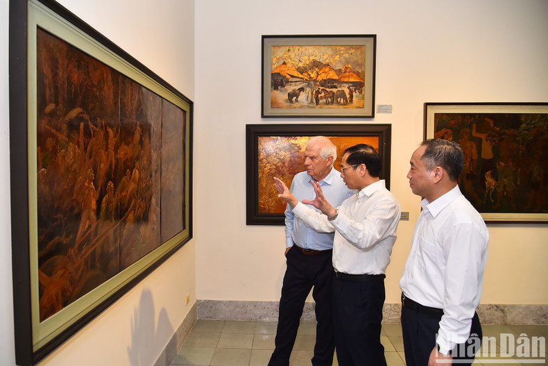 El canciller vietnamita presenta al visitante el contexto histórico del cuadro &quot;Arrastrar artillería&quot; pintado por el artista Duong Huong Minh.
