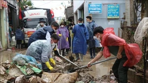 Las fuerzas armadas ayudan a los pobladores a limpiar las calles. (Foto: VNA)