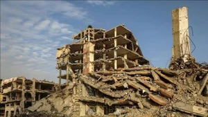 La gente camina entre los escombros de los edificios destruidos por el conflicto en la ciudad de Gaza. (Foto: Xinhua/VNA)