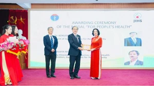La profesora asociada y doctora Nguyen Thi Lien Huong, viceministra de Salud, entrega la Medalla Conmemorativa “Por la Salud del Pueblo” a expertos del JIHS.