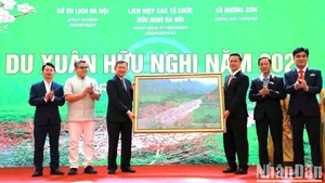 Representantes de la comuna de Huong Son ofrecen a la delegación una pintura del arroyo Yen en el conjunto paisajístico de Huong Son.