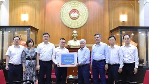Do Van Chien, miembro del Buró Político y del Secretariado del Comité Central del Partido Comunista y presidente del Comité Central del Frente de la Patria de Vietnam, recibe el donativo de Nhan Dan. (Foto: Nhan Dan)