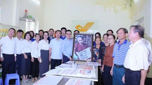 Le Quoc Minh, presidente-editor de Nhan Dan, entrega un cuadro del tío Ho leyendo el periódico Nhan Dan a los cuadros, miembros del Partido y habitantes de la comuna de Tan Hung en la oficina de correo y centro cultural de la comuna de Tan Hung.