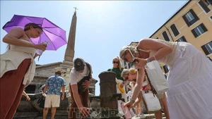 La gente bebe agua para refrescarse en un día caluroso en Roma, Italia. (Foto: Xinhua/VNA)