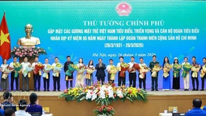 El primer ministro Pham Minh Chinh entrega flores para felicitar a los jóvenes vietnamitas destacados. (Foto: VNA)