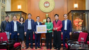 El presidente-editor del periódico Nhan Dan, Le Quoc Minh, entrega la asistencia a las víctimas de las inundaciones.