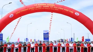 El primer ministro Pham Minh Chinh y los delegados cortan la cinta de inauguración del puente Phong Chau.