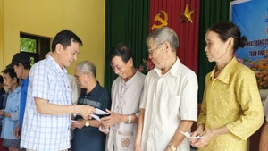 Un representante del periódico Nhan Dan en Quang Tri entrega donaciones en efectivo a los habitantes de la aldea de Hoi Ky, comuna de Nam Hai Lang.
