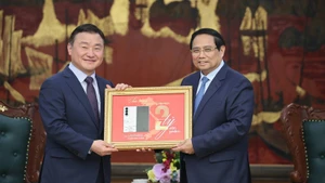 El primer ministro Pham Minh Chinh (derecha) entrega una placa conmemorativa de la producción del teléfono móvil número dos mil millones de Samsung en Vietnam a Roh Tae Moon (Foto: baochinhphu.vn)