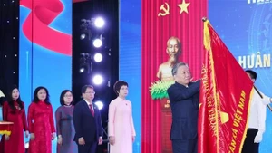 El secretario general del Partido Comunista de Vietnam, To Lam, coloca la Orden Ho Chi Minh en la bandera tradicional de la VNA. (Foto: VNA)