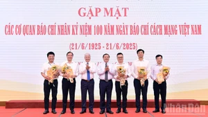 El presidente del Comité Central del Frente de la Patria de Vietnam, Do Van Chien y el subjefe de su Comisión de Propaganda, Educación y Movilización de Masas del Partido, Lai Xuan Mon (3º y 4º a la izquierda) entregan flores a los representantes las agencias de prensa en el evento.