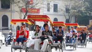 Turistas extranjeros experimentan un recorrido en triciclo alrededor del lago Hoan Kiem en Hanói (Foto: VNA)
