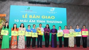 Una representante del periódico Nhan Dan entrega una placa simbólica de diez casas de caridad a las mujeres en situación difícil de la localidad. (Foto: HOANG TRUNG)