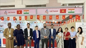 El consejero comercial Bui Trung Thuong (cuarto desde la izquierda) posa para una foto con invitados nacionales e internacionales que visitan el stand. (Foto: VNA)