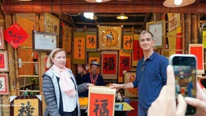 Los turistas internacionales disfrutan de la tradición de recibir caligrafía auspiciosa a principios de año. (Foto: VNA)