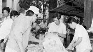 Ciudadanos de Hanoi compran el "Noticiero vespertino" de la VNA para seguir las noticias de la clausura del VII Congreso Nacional del Partido (17 de julio de 1991). Foto: Huu Oai - VNA