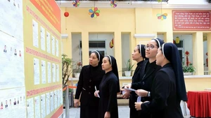 Monjes de la Congregación de las Hermanas de la Caridad de la Santa Cruz consultan la lista de candidatos en el colegio electoral No. 1, barrio de Hoan Kiem, Hanói. (Foto: VNA)