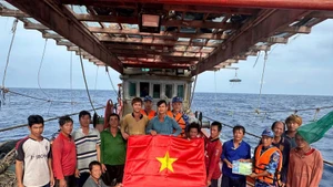 Las fuerzas de seguridad marítima de Ciudad Ho Chi Minh entregan la bandera nacional y difunden medidas preventivas contra la pesca INDNR a los marineros. (Foto: VNA)
