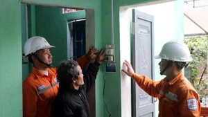 Electricistas enseñan a un residente equipos eléctricos en su nuevo hogar. (Foto: VNA)