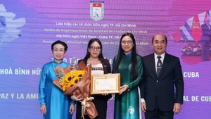 La cónsul general de Cuba en Ciudad Ho Chi Minh, Ariadne Feo Labrada (segunda a la izquierda), recibe la insignia “Por la paz y la amistad entre los pueblo” de la VUFO en el evento. (Foto: VNA)