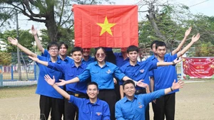 Miembros de la Unión de Jóvenes Comunistas Ho Chi Minh en Cuba izan la bandera nacional. (Foto: VNA)
