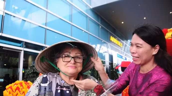 Nguyen Thi Duyen, representante de Anex Tour Vietnam, obsequia un sombrero cónico tradicional a una visitante rusa. (Foto: tuoitre.vn)