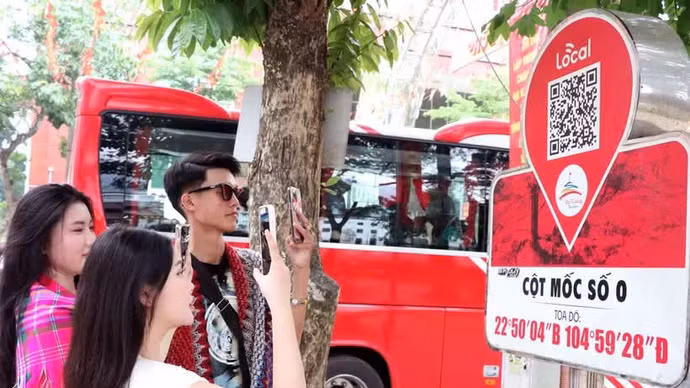 Los visitantes escanean un código QR en el marcador del kilómetro 0 de la provincia de Ha Giang para acceder a información turística. (Foto: VNA)