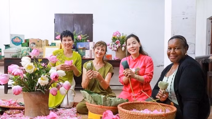 Los turistas experimentan la artesanía tradicional de infusionar té con flores de loto de Quang An. (Foto: VNA)