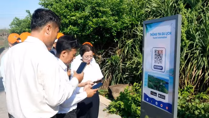 Un turista escanea un código QR para acceder rápidamente a la información turística en el mástil de la bandera de soberanía de la zona especial de Phu Quy (Lam Dong). (Foto: VNA)