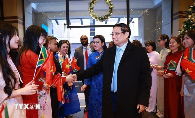 Funcionarios y personal de la Embajada y la comunidad vietnamita en Sudáfrica dAn la bienvenida al primer ministro Pham Minh Chinh y a su esposa. (Foto: VNA)