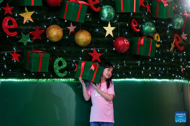 Una niña posa para una fotografía junto a decoraciones navideñas en un centro comercial de Yangon, Myanmar.
