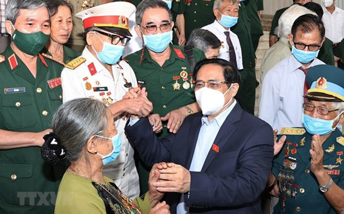 El primer ministro de Vietnam, Pham Minh Chinh, se encuentra con las personas con méritos revolucionarios. (Fotografía: VNA)