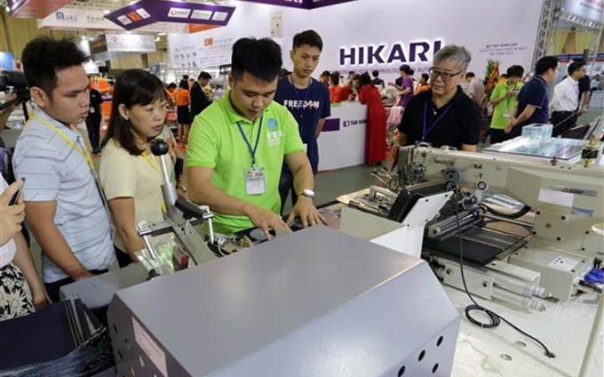 Visitantes recorren en una exposición de equipos y maquinarias de confección textil en Vietnam (Fuente: VNA)