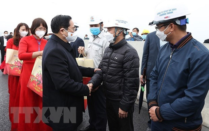 El primer ministro Pham Minh Chinh felicita a ingenieros y trabajadores de la construcción de la autopista Van Don - Mong Cai en Quang Ninh. (Fotografía: VNA)